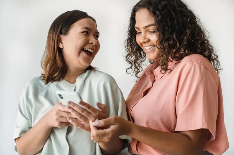 Duas amigas olhando o celular juntas e rindo